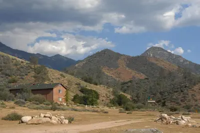 a house in a field with mountains in the background at Corral Creek Lodge in Kernville