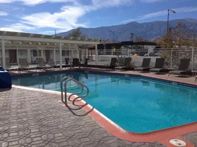 a large swimming pool with chairs and mountains in the background at Historic Dow Hotel in Lone Pine