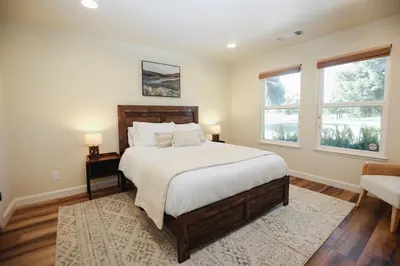 a bedroom with a large bed and two windows at Riverfront Beauty with Pickle Ball Court in Kingsburg