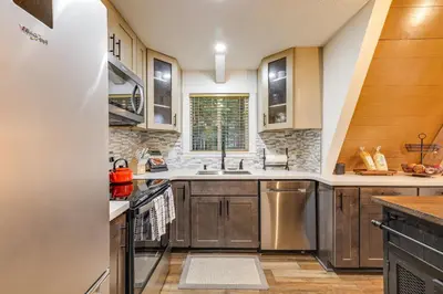 a kitchen with wooden cabinets and a sink at 3 Mi to Calaveras Big Trees Cabin with Fire Pit! in Arnold