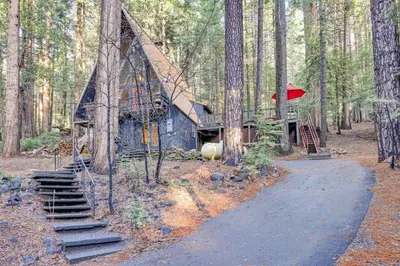 a house in the woods with a path leading to it at 3 Mi to Calaveras Big Trees Cabin with Fire Pit! in Arnold