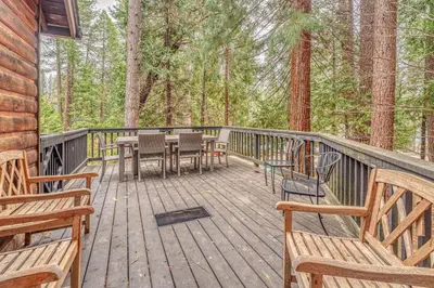 a wooden deck with benches and tables in the woods at Oso Borracho in Arnold