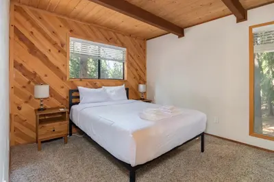 a bedroom with a white bed and a wooden ceiling at Moonlit Pines in Camp Connell