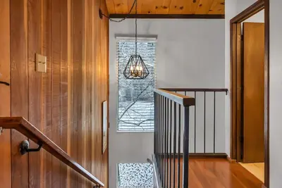 a hallway with a staircase with a window and a chandelier at 3BD Three Minutes from King Beach in Kings Beach
