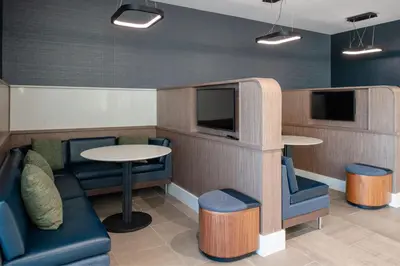 a waiting room with chairs and a table and a tv at Courtyard by Marriott Modesto North in Modesto