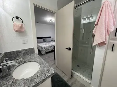 a bathroom with a sink and a glass shower at Entire Modern House with King bed & 65inTV in Carmichael