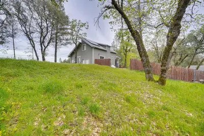 a house on top of a grassy hill with trees at Bay Area Escape on 5 Acres Pet Friendly, Views in Pilot Hill