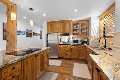 a kitchen with wooden cabinets and a stainless steel refrigerator at Rocky Point # 14 Palisades Townhome - Ski Shuttle w Tennis! in Olympic Valley