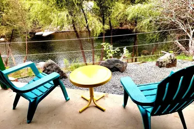 a patio with three chairs and a yellow table and a table at Retro Casita on the River! only 1 min to SNP gate! Riverfront with swimming in Three Rivers