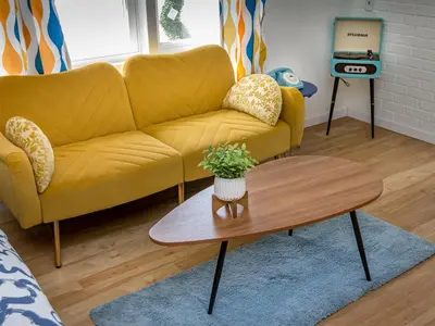 a living room with a yellow couch and a coffee table at Retro Casita on the River! only 1 min to SNP gate! Riverfront with swimming in Three Rivers