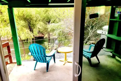three chairs and a table on a porch with a view at Retro Casita on the River! only 1 min to SNP gate! Riverfront with swimming in Three Rivers