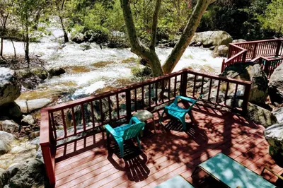 two benches sitting on a deck next to a river at River Retreat Cabin in Three Rivers - near SNP in Three Rivers