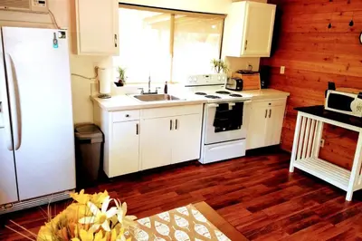 a kitchen with white cabinets and a sink and a refrigerator at River Retreat Cabin in Three Rivers - near SNP in Three Rivers