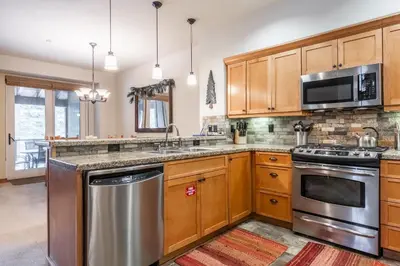 a kitchen with wooden cabinets and stainless steel appliances at Upscale 4 Bed, 3 Bath at the Woodwinds with Amazing Mountain Views and Golf Course Access and private hot tub and garage sleeps 10 in Mammoth Lakes