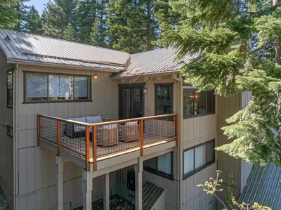 a house with a large deck with windows at The Pinecrest Retreat- 10 mins to NorthStar! Hot Tub, Large Deck, Views, and Games in Tahoe Vista