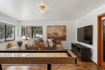 a living room with a couch and a tv at The Pinecrest Retreat- 10 mins to NorthStar! Hot Tub, Large Deck, Views, and Games in Tahoe Vista