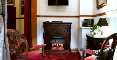 a fireplace in a room with two chairs and a table at Bella Vista Bed and Breakfast in Coloma