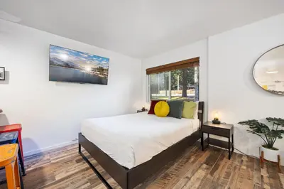 a white bedroom with a bed and a window at Striking Queen Deluxe Studio w/Kitchenette #114 at Donner Lake Village in Truckee
