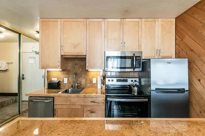 a kitchen with wooden cabinets and a stainless steel refrigerator at Lovely Studio w/Kitchen and Partial Lake View #122 at Donner Lake Village in Truckee