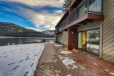 a building with snow on the ground next to a lake at Cozy King Studio w/Lake View #145 at Donner Lake Village in Truckee