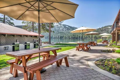 a group of picnic tables with umbrellas and a lake at Cozy Studio wKitchen #217 at Donner Lake Village in Truckee