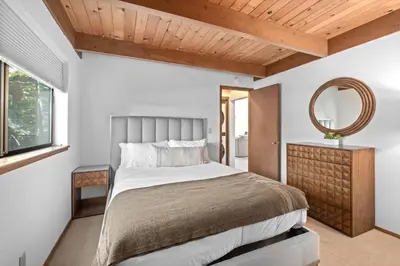 a bedroom with a large bed and a mirror at Waves End Lakefront - 3BR Tahoe Vista w Private Sandy Beach, Walk to Town! in Tahoe Vista