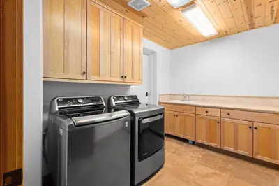 a kitchen with a black dishwasher and wooden cabinets at Copperleaf Lodge by Tahoe Getaways - Updated 5BR Alpine Meadows Chalet w Private Hot Tub, Ski Shuttle! in Alpine Meadows
