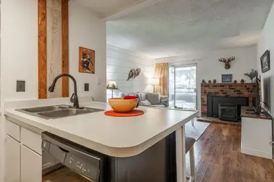 a kitchen with a sink and a living room at Cozy Cabin-Style Condo in Central Location in Mammoth Lakes