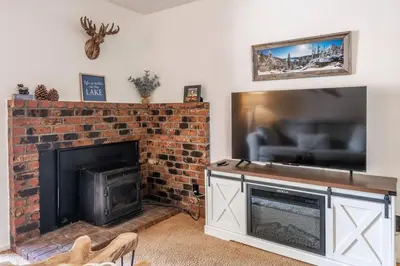 a living room with a fireplace and a large television at Cozy Cabin-Style Condo in Central Location in Mammoth Lakes