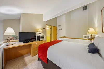 a hotel room with a bed and a flat screen tv at Palisades Tahoe Lodge Rentals Studio Loft #307 in Olympic Valley