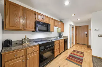 a kitchen with wooden cabinets and a stove top oven at Palisades Tahoe Lodge Rentals Studio Loft #306 in Olympic Valley