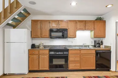 a kitchen with wooden cabinets and a white refrigerator at Palisades Tahoe Lodge Rentals Studio Loft #306 in Olympic Valley