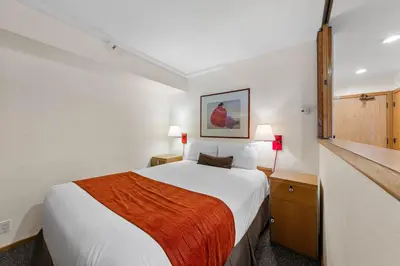 a hotel room with a bed with a orange blanket at Palisades Tahoe Lodge Rentals Studio Loft #317 in Olympic Valley