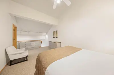 a white bedroom with a bed and a chair at Palisades Tahoe Lodge Rentals Studio Loft #345 in Olympic Valley