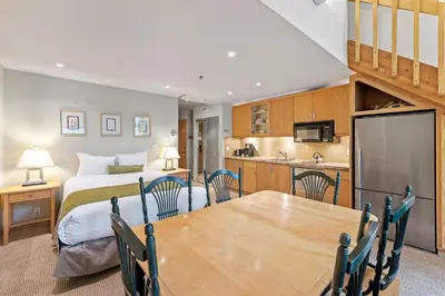 a room with a bed and a table and a kitchen at Palisades Tahoe Lodge Rentals Studio Loft #349 in Olympic Valley