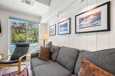 a living room with a gray couch and a chair at Palisades Tahoe Lodge Rentals Premium Studio Loft #333 in Olympic Valley