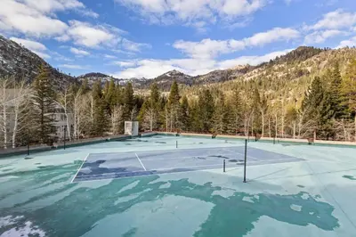 a tennis court with trees and mountains in the background at Palisades Tahoe Lodge Rentals Premium Studio Loft #333 in Olympic Valley