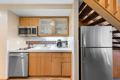a kitchen with a stainless steel refrigerator and wooden cabinets at Palisades Tahoe Lodge Rentals Studio Loft #334 in Olympic Valley