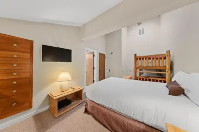a bedroom with a bed and a dresser and a crib at Palisades Tahoe Lodge Rentals Premium Studio Loft #313 in Olympic Valley