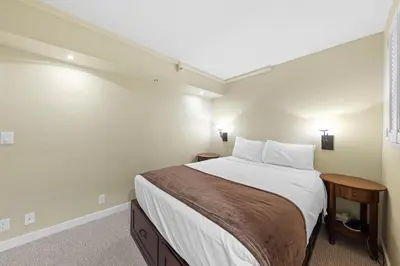 a bedroom with a bed with white sheets and pillows at Palisades Tahoe Lodge Rentals Premium Studio Loft #313 in Olympic Valley