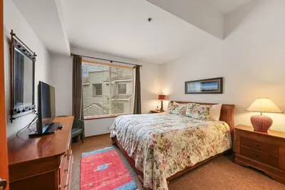 a bedroom with a bed and a tv and a window at Palisades Tahoe Lodge Rentals Two Bedroom #422 in Olympic Valley