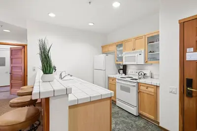 a kitchen with white appliances and wooden cabinets at Palisades Tahoe Lodge Rentals Two Bedroom #703 in Olympic Valley