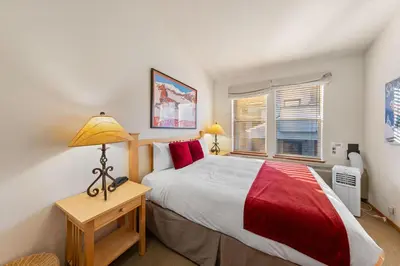 a bedroom with a bed and a lamp and a window at Palisades Tahoe Lodge Rentals Two Bedroom #800 in Olympic Valley