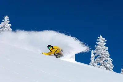 a man riding a snowboard down a snow covered slope at Palisades Tahoe Lodge Rentals Two Bedroom #800 in Olympic Valley