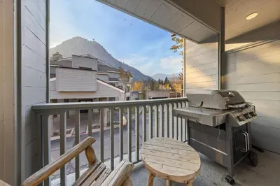a grill on a balcony with a table and a bench at Palisades Tahoe Lodge Rentals Two Bedroom #800 in Olympic Valley