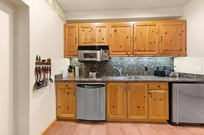 a kitchen with wooden cabinets and a sink at Palisades Tahoe Lodge Rentals Premium Studio #243 in Olympic Valley