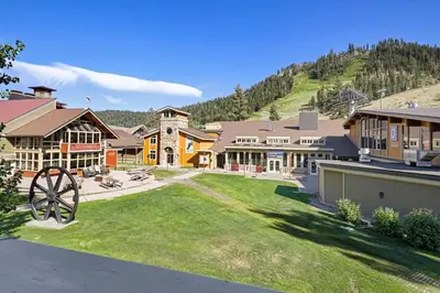 a house with a large yard in front of a mountain at Palisades Tahoe Lodge Rentals Two Bedroom #814 in Olympic Valley