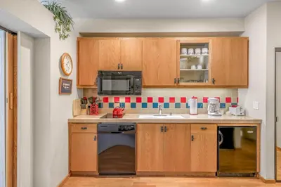 a kitchen with wooden cabinets and a sink at Palisades Tahoe Lodge Rentals Studio #143 in Olympic Valley