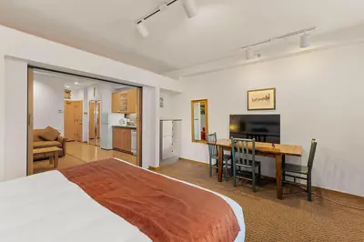 a bedroom with a bed and a table and a kitchen at Palisades Tahoe Lodge Rentals Studio #144 in Olympic Valley