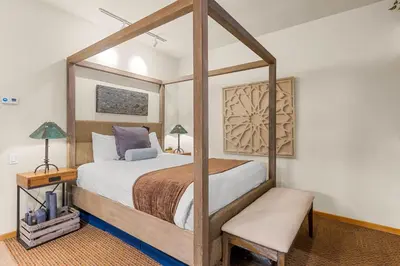 a bedroom with a wooden canopy bed with a chair at Palisades Tahoe Lodge Rentals Studio #146 in Olympic Valley